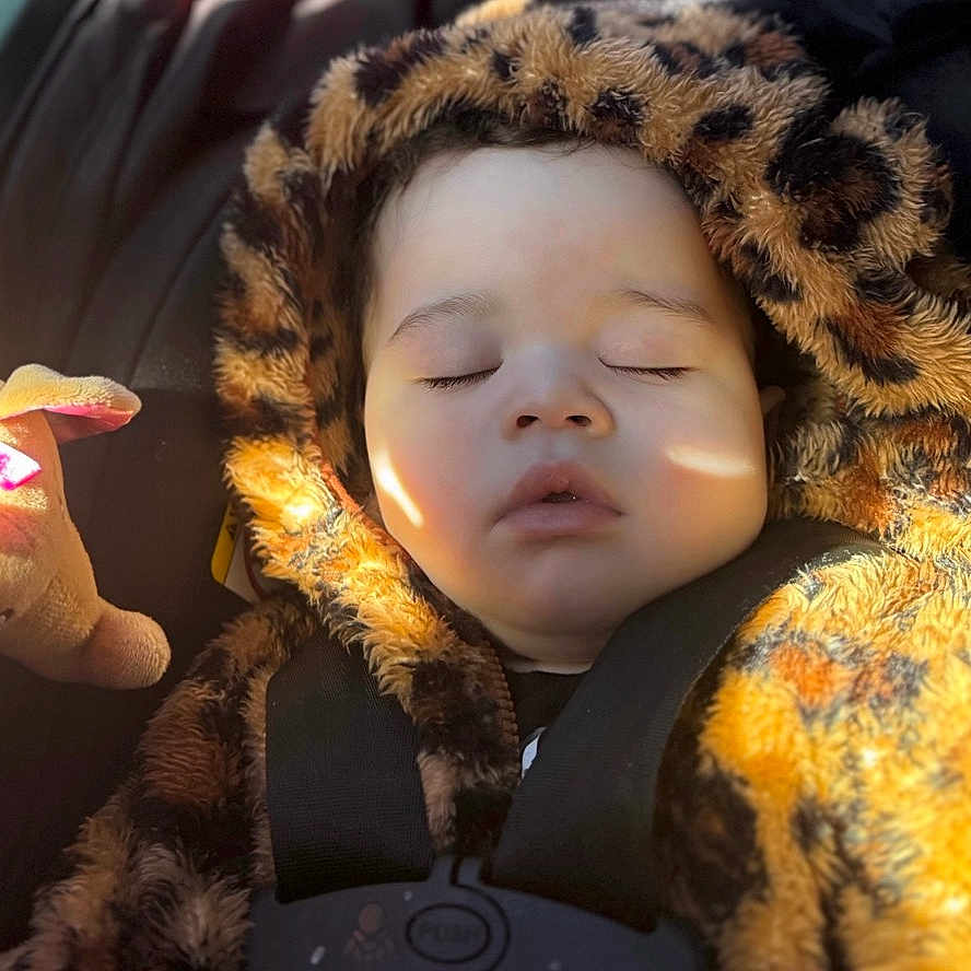 Zoë is registered to the contest to win money with this photo: baby, blanket, bonnet, clothing, coat, electronics, face, glove, hair, hat, head, hood, jacket, person, photography, portrait, sad, sleeping, toy, yawning