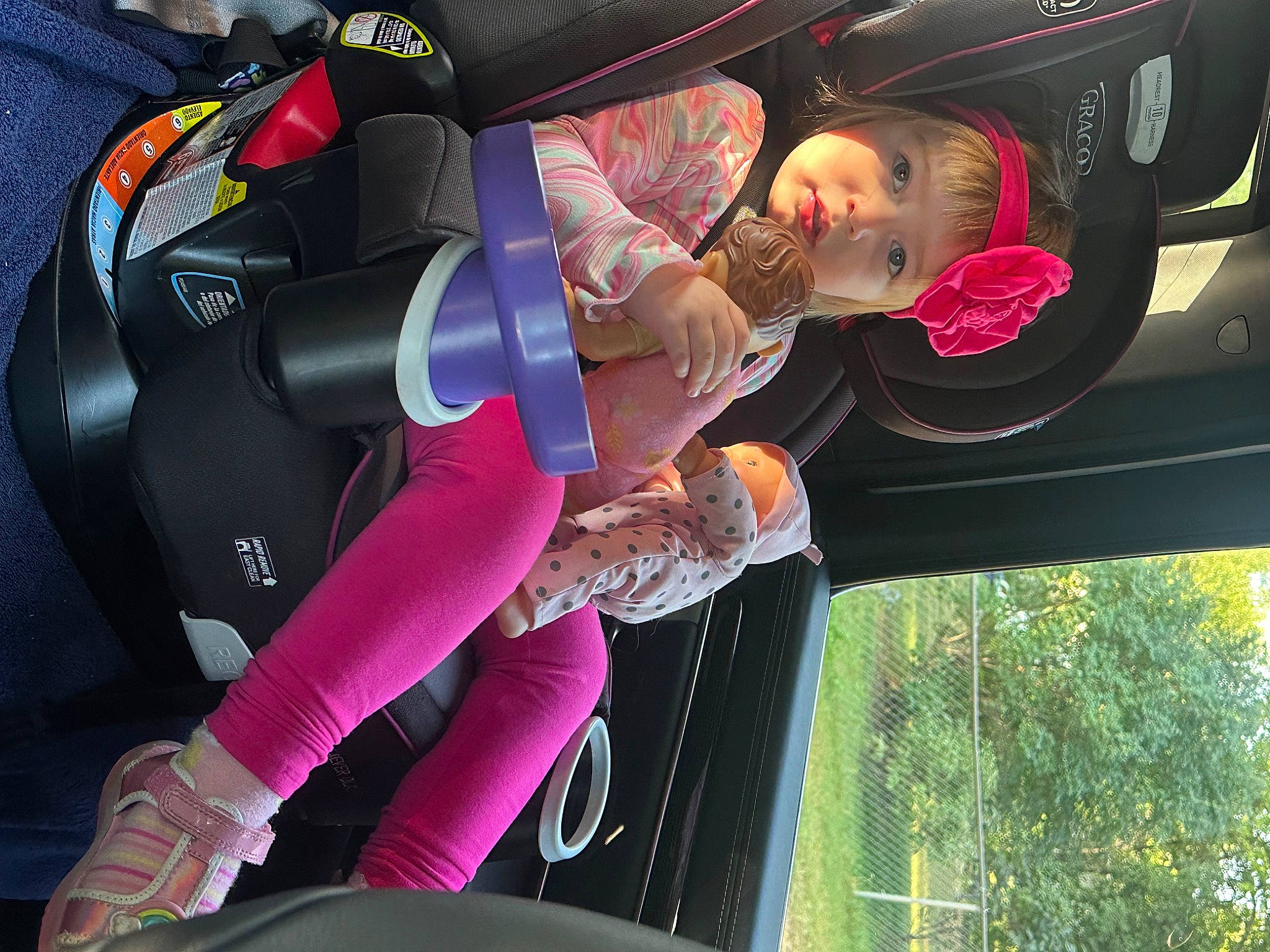 Noelle is registered to the contest to win money with this photo: auto_part, automotive_design, automotive_exterior, automotive_lighting, bumper, carmine, family_car, fun, glove, headwear, magenta, motor_vehicle, person, pink, recreation, tire, toddler, tree, trunk, vehicle