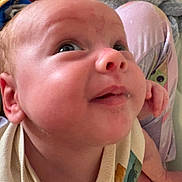 Jayson is registered to the contest to win money with this photo: baby, face, infant, closeup, smile, child, person, skin, eye, nose, ear, clothing, pattern, pajamas, hand, leg, background, indoor, expression, curious