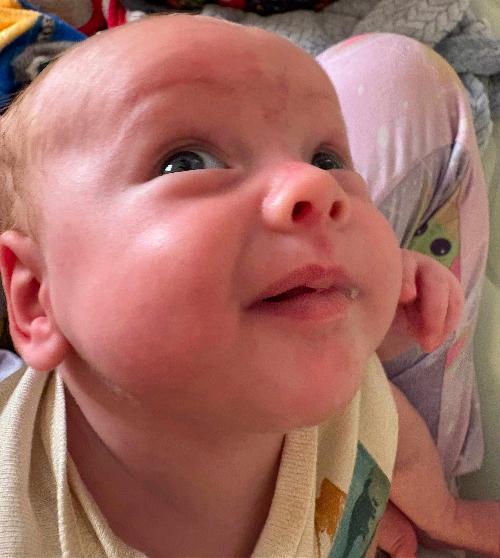 Jayson is registered to the contest to win money with this photo: baby, face, infant, closeup, smile, child, person, skin, eye, nose, ear, clothing, pattern, pajamas, hand, leg, background, indoor, expression, curious