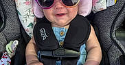 Harper is registered to the contest to win money with this photo: baby, child, sunglasses, car_seat, bow, smile, infant, seat_belt, clothing, denim, pink, floral, safety, cute, headwear, accessory, happy, portrait, indoors, person