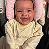 baby, infant, smile, happy, face, clothing, yellow_sweater, blanket, cushion, car_seat, child, cute, portrait, indoors, skin, person, young, comfort, head_support, joy