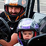 child, adult, helmet, go_kart, racing, seatbelt, race_track, vehicle, safety_gear, outdoor, person, sport, family, transportation, helmet_visors, black_clothing, purple_helmet, orange_helmet, driving, fun