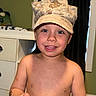 Nolan is registered to the contest to win money with this photo: baby, baseballcap, bodypart, cap, clothing, couch, dress, face, finger, furniture, hand, hat, head, indoors, mouth, person, photography, portrait, skin, sunhat