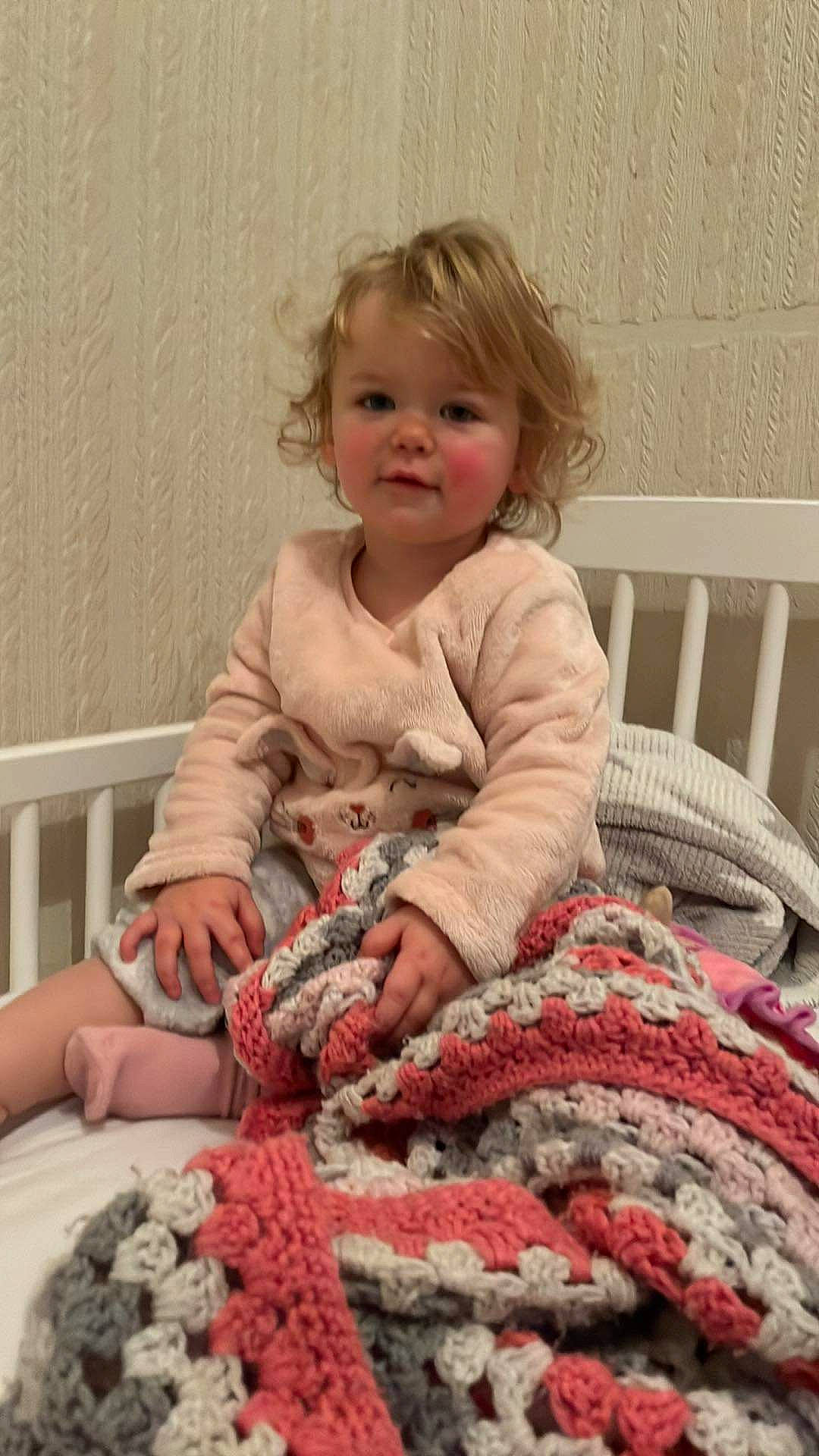 Lily is registered to the contest to win money with this photo: baby, baby_toddler_clothing, chair, cheek, child, comfort, craft, crochet, face, linens, pattern, person, pink, room, sitting, sleeve, smile, thread, toddler, wool