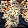 Knox is registered to the contest to win money with this photo: baby, infant, pajamas, dinosaur_pattern, blanket, sports_theme, bed, tummy_down, sleepwear, footed_pajamas, indoor, child, soft_fabric, cute, young, resting, cozy, head, feet, sleep