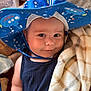 Graham Brewer is registered to the contest to win money with this photo: baby, child, hat, blue_hat, blanket, plaid_blanket, smile, face, skin, arm, clothing, sleeveless_shirt, indoors, soft_texture, cute, headwear, infant, baby_fashion, portrait, cozy