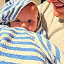 Mariette participe au concours pour gagner de l'argent avec cette photo : baby, towel, striped_towel, blue, white, face, eyes, adult, glasses, smile, person, closeup, indoor, portrait, expression, child, wrapped, cozy, candid, human