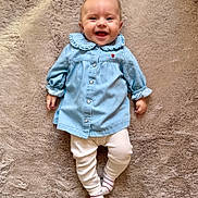 Victoire a rejoint le concours — aidez-le/la à gagner de superbes lots ! baby, infant, smiling, blue_dress, leggings, striped_socks, lying_down, plush_rug, indoor, cute, happy, child, portrait, buttoned_clothing, soft_texture, small_hands, head, face, eyes, mouth