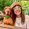 Mila a rejoint le concours — aidez-le/la à gagner de superbes lots ! woman, dog, hat, glasses, outdoor, picnic_table, greenery, smile, pet, collar, wooden_table, canopy, glass_of_wine, necklace, casual_clothing, daylight, friendship, nature, portrait, relaxing