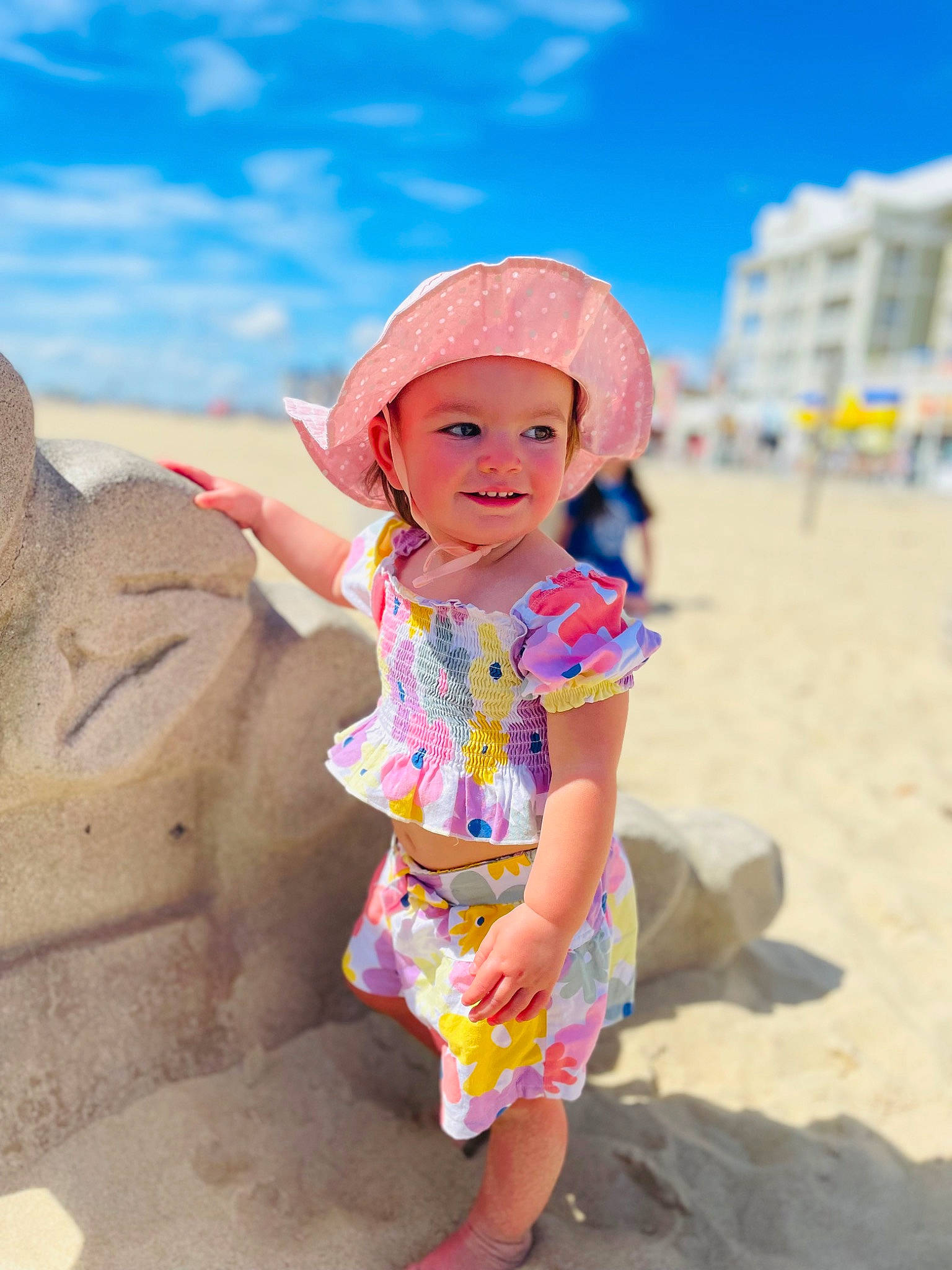 Adilynn is registered to the contest to win money with this photo: beach, beauty, body_of_water, cloud, fun, happy, hat, headwear, joy, landscape, leisure, natural_environment, people_on_beach, person, pink, sand, shorts, sky, smile, summer