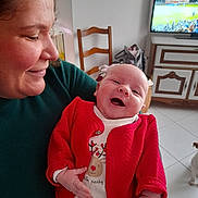 Solyne a rejoint le concours — aidez-le/la à gagner de superbes lots ! baby, adult, smiling, red_cardigan, indoor, chair, television, dog, floor_tiles, cabinet, person, happy, holding, home, furniture, portrait, cute, infant, cozy, family