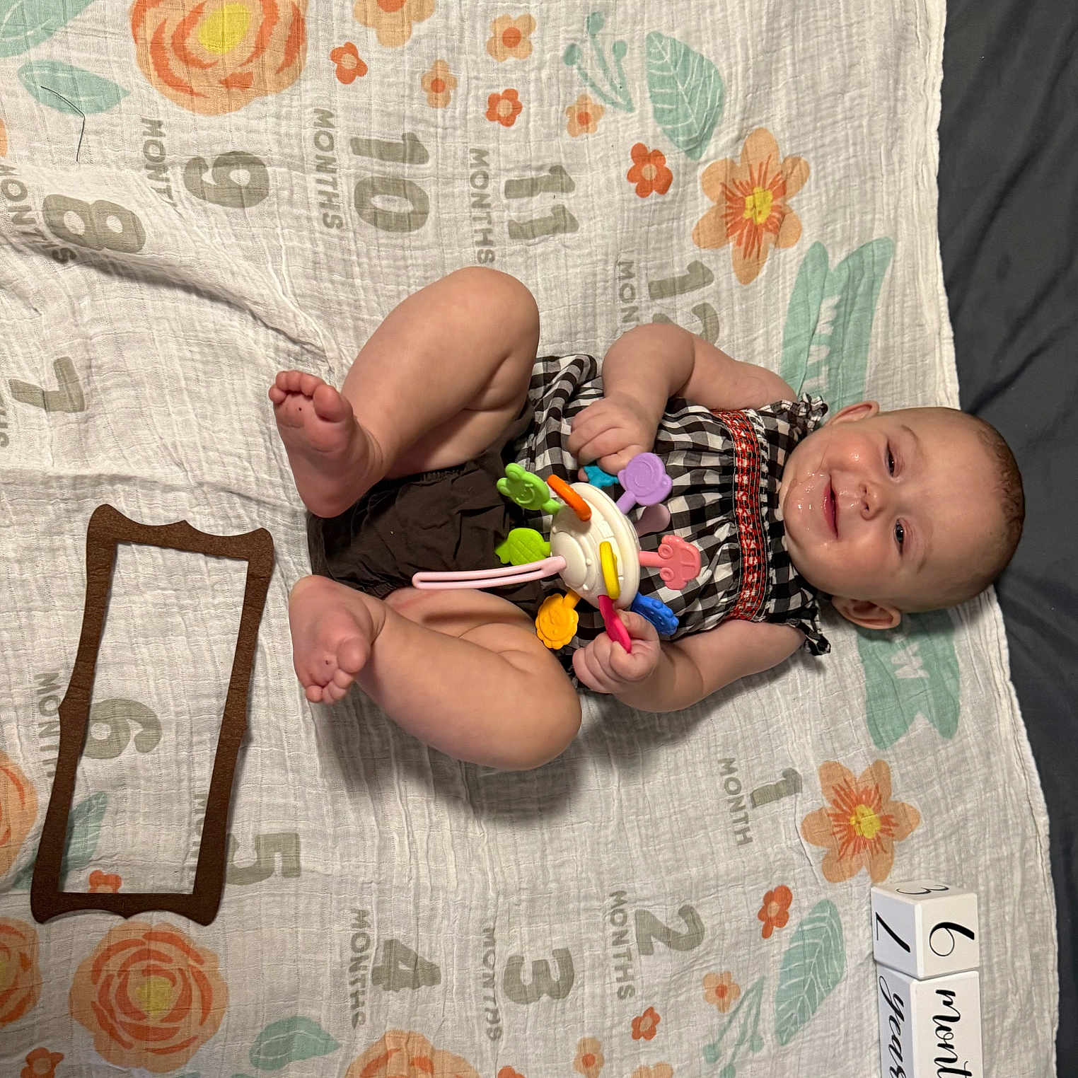 Charlotte joined the competition — help win amazing prizes! baby, child, clothing, colorful, cute, drool, fabric, flowers, happy, indoors, infant, lying_down, milestone_blanket, months, numbers, person, playful, portrait, smiling, toy