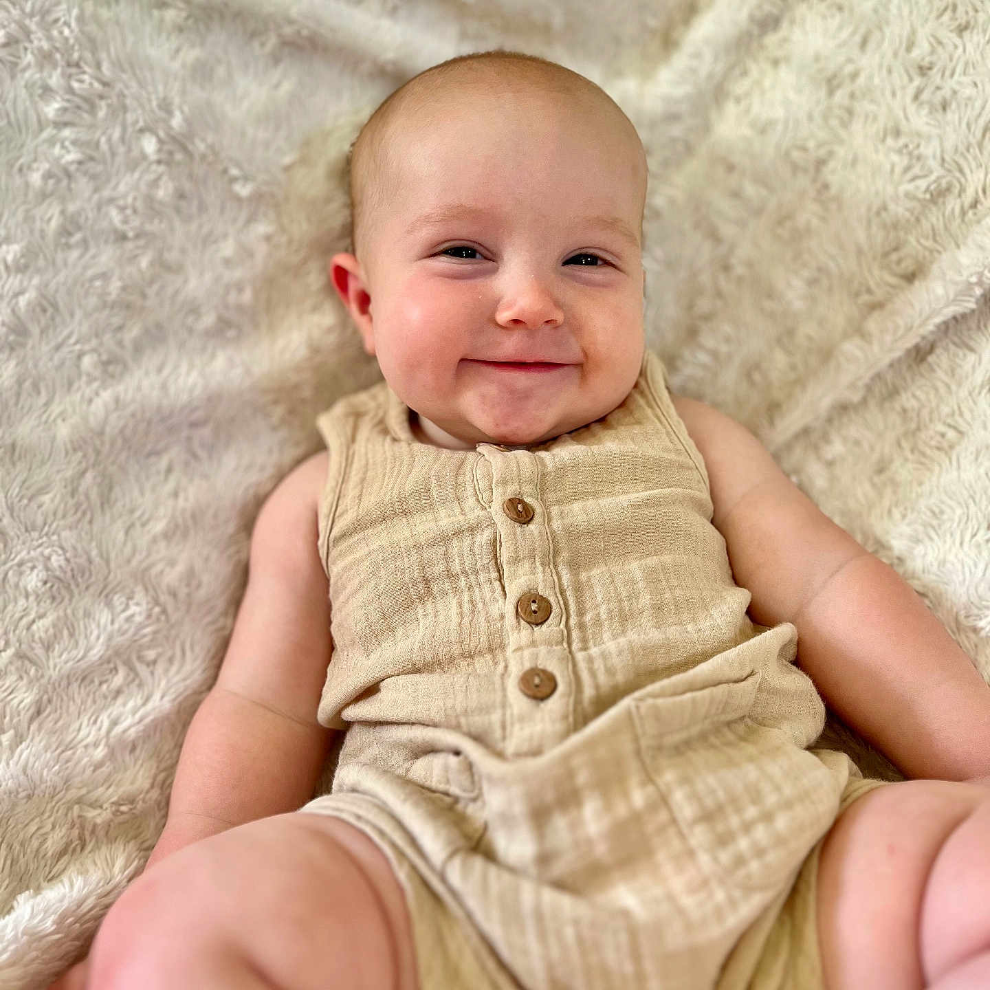 Mason is registered to the contest to win money with this photo: baby, beige, buttoned_clothing, child, chubby_cheeks, cute, face, fluffy_blanket, happy, indoors, infant, light, portrait, relaxed, romper, sitting, skin, smiling, soft_texture, young_child