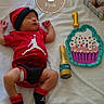 baby, infant, newborn, child, sleeping, portrait, birthday, one_month, red_outfit, hat, blanket, stuffed_animals, balloons, cupcake, celebration, bed, indoor, toys, bottle, photography