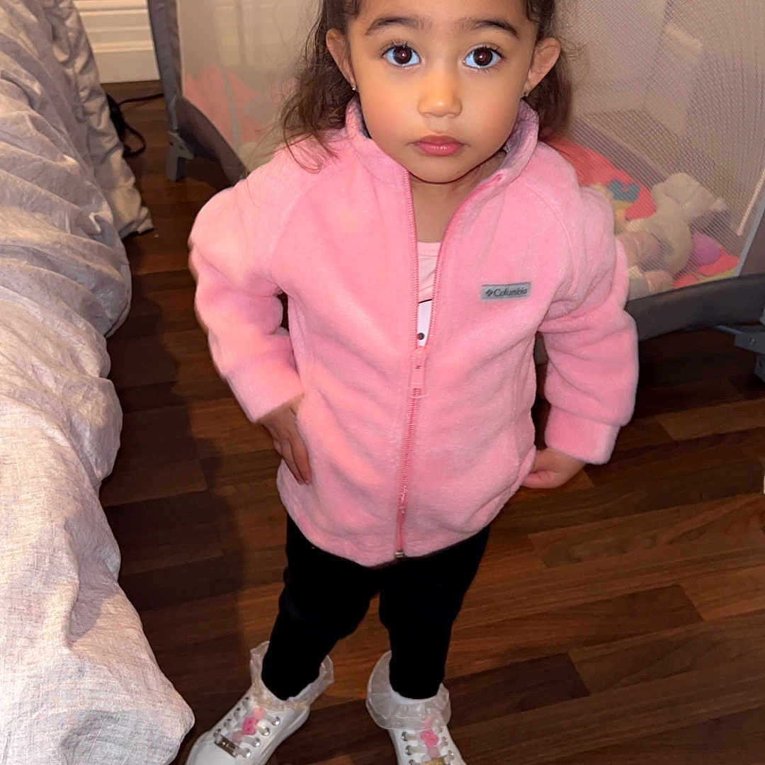 Delaney is registered to the contest to win money with this photo: child, clothing, couch, crib, face, female, footwear, furniture, girl, hardwood, head, indoors, infantbed, interiordesign, knitwear, person, shoe, sneaker, sweater, wood