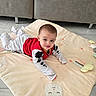 baby, child, infant, play_mat, bunny, soft_toy, floor, sofa, red_clothing, white_clothing, cute, indoor, flooring, smiling, looking, lying_down, person, young_child, head, eyes