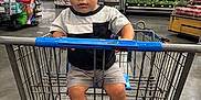Lahiam joined the competition — help win amazing prizes! toddler, child, shopping_cart, supermarket, curly_hair, casual_clothing, shorts, sneakers, aisle, produce, shelves, grocery_store, indoor, floor, person, retail, shopping, young_child, store, shopping_trip
