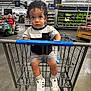toddler, child, shopping_cart, supermarket, curly_hair, casual_clothing, shorts, sneakers, aisle, produce, shelves, grocery_store, indoor, floor, person, retail, shopping, young_child, store, shopping_trip