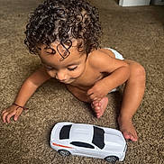 Lahiam joined the competition — help win amazing prizes! child, toddler, toy_car, curly_hair, carpet, indoor, diaper, playing, crawling, brown_skin, cute, baby, floor, car, foot, hand, room, door, home
