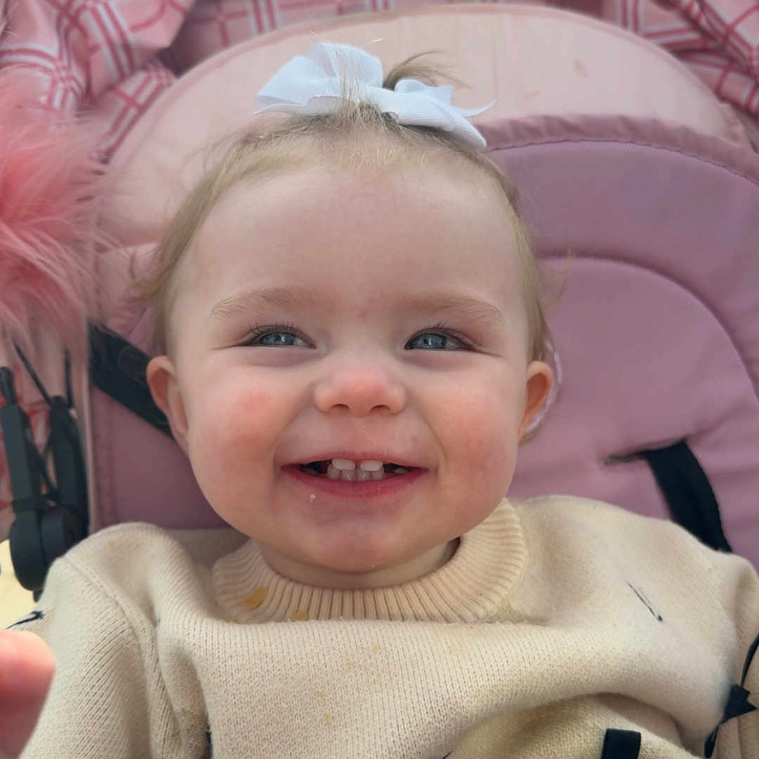 Elsie Laney is registered to the contest to win money with this photo: baby, bodypart, car, car_interior, clothing, coat, face, happy, head, jacket, knitwear, laughing, mouth, person, photography, portrait, smile, stroller, sweater, teeth