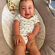 Nathan a rejoint le concours — aidez-le/la à gagner de superbes lots ! baby, infant, smiling, sitting, plush_toy, giraffe, baby_seat, cushion, clothing, onesie, happy, cute, child, indoors, person, skin, face, hand, leg, footwear