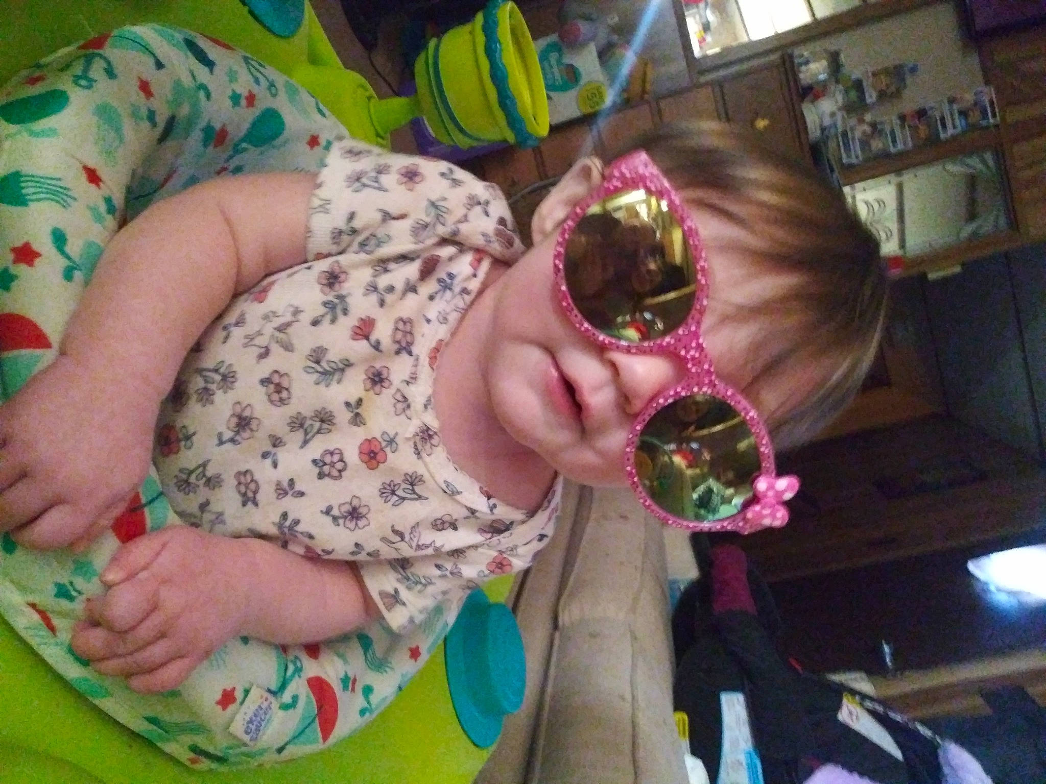 Armani is registered to the contest to win money with this photo: baby, baby_toddler_clothing, child, design, eyewear, finger, fun, green, human_body, leisure, nail, pattern, person, picture_frame, pink, play, sitting, sunglasses, textile, toddler