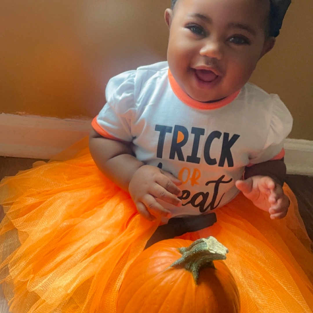 Damoura is registered to the contest to win money with this photo: accessories, baby, clothing, costume, face, food, glasses, head, hosiery, pants, person, photography, plant, portrait, pottedplant, produce, pumpkin, squash, t_shirt, vegetable