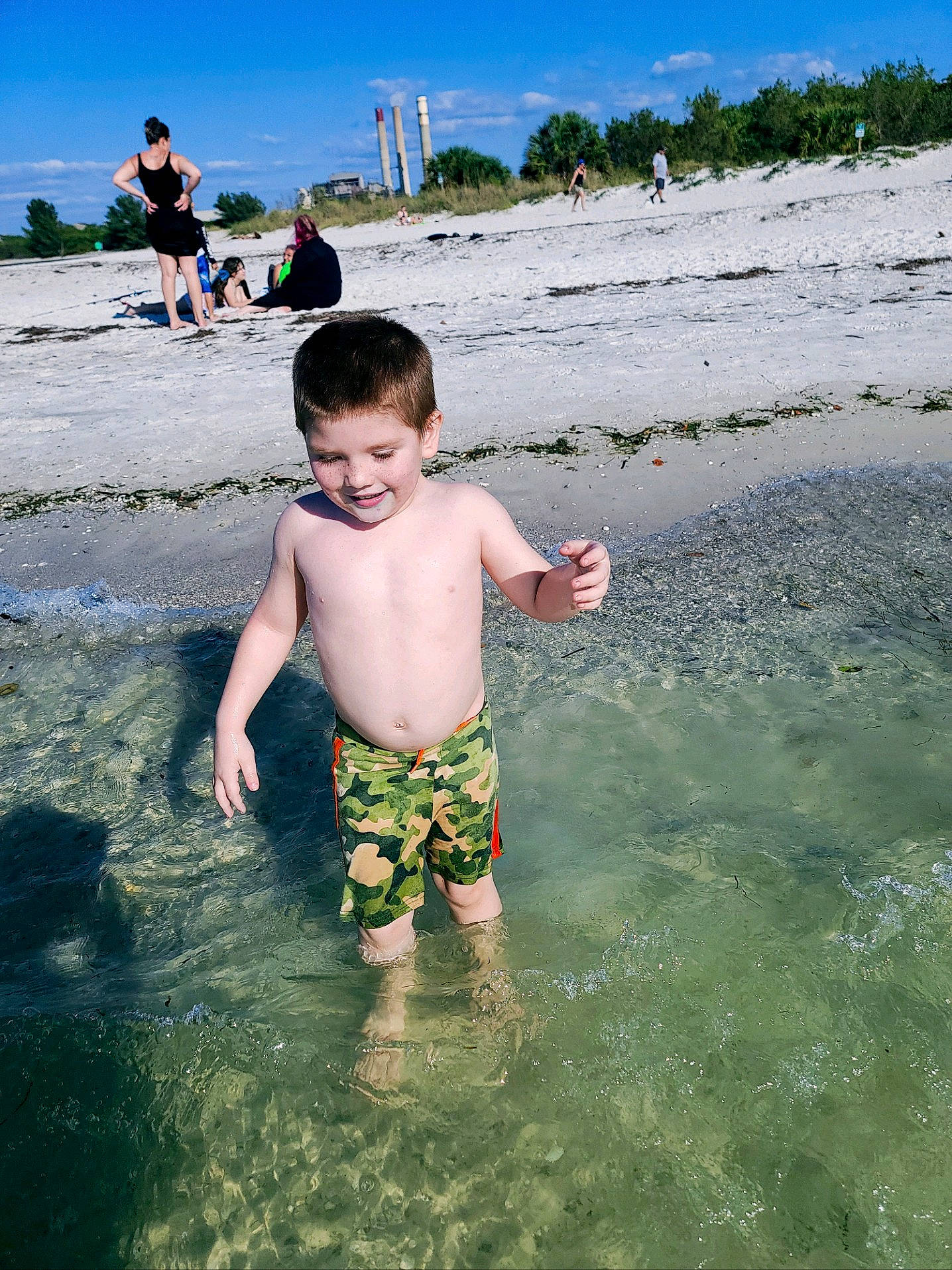 Aydin is registered to the contest to win money with this photo: barefoot, bathing, beach, fun, happy, holiday, joy, leg, leisure, people_in_nature, people_on_beach, person, plant, recreation, shorts, sky, toddler, tree, trunks, water