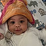 baby, infant, hat, blanket, animal_print, cute, child, smiling, lying_down, white_clothing, indoors, face, headwear, soft_texture, pattern, monkey, rhino, tiger, toy, closeup