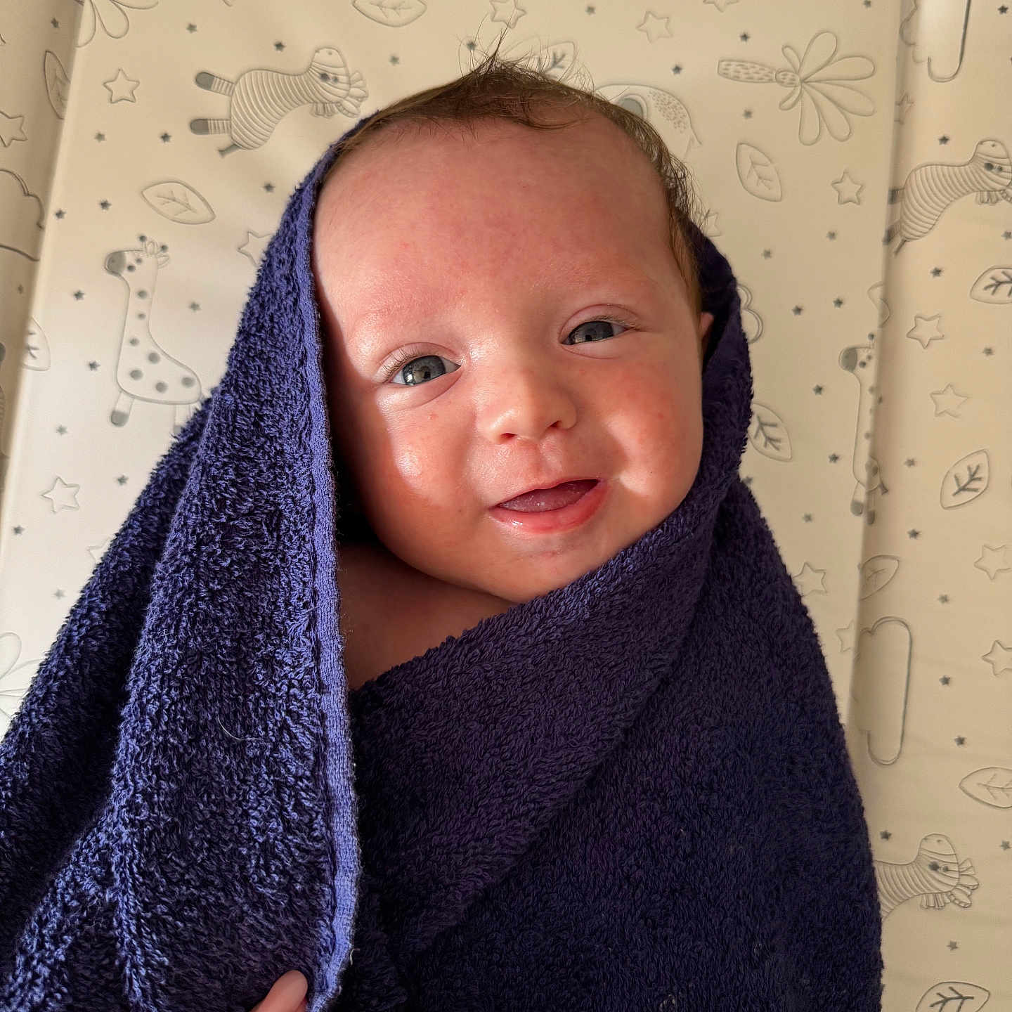 Oakley joined the competition — help win amazing prizes! baby, background, blue_eyes, changing_pad, child, cozy, cute, face, giraffe_pattern, hand, happy, indoor, infant, newborn, person, skin, smile, soft_texture, towel, wrapped