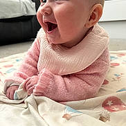 Millie joined the competition — help win amazing prizes! baby, infant, smiling, pink_sweater, bib, blanket, indoor, happy, cute, child, face, hands, lying_down, soft_toys, cozy, pattern, mouth_open, expression, skin, young