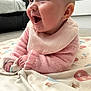 baby, infant, smiling, pink_sweater, bib, blanket, indoor, happy, cute, child, face, hands, lying_down, soft_toys, cozy, pattern, mouth_open, expression, skin, young