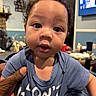 baby, blue_shirt, casual, child, close_up, curly_hair, cute, expression, eyes, face, furniture, hand, home, indoor, living_room, person, portrait, skin, television, young_child