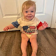 Easton is registered to the contest to win money with this photo: baby, barefoot, bodypart, clothing, door, face, finger, hand, hardwood, head, indoors, interiordesign, pants, person, photography, portrait, shorts, sitting, t_shirt, wood