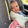 baby, child, car_seat, blanket, smile, face, window, car, interior, clothing, pink, white, fur, cute, infant, seatbelt, hair_clip, happy, portrait, young_child