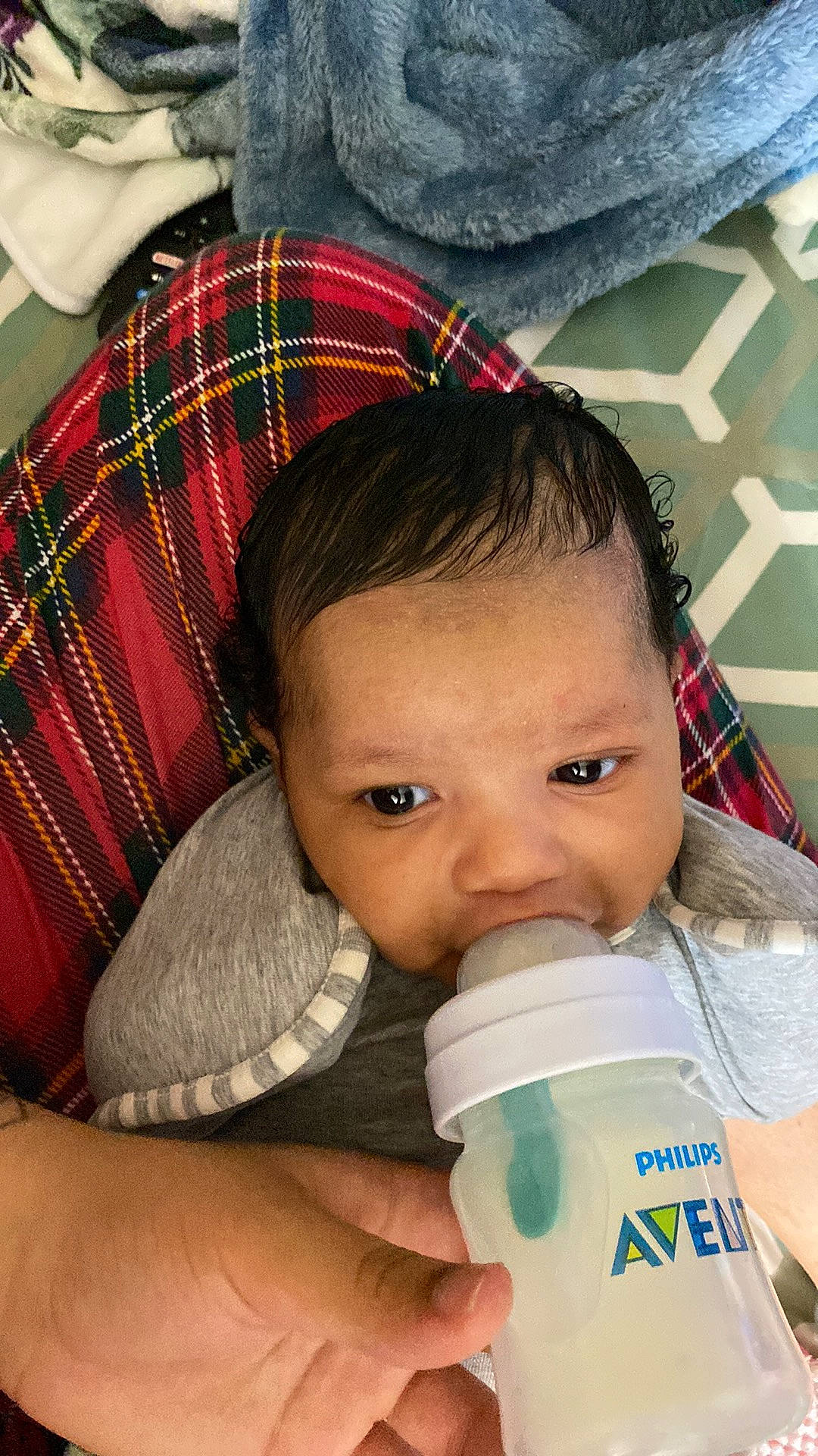 Layoni is registered to the contest to win money with this photo: baby, baby_toddler_clothing, cheek, child, comfort, drinkware, eyelash, face, green, hairstyle, happy, head, lip, nose, person, plaid, plastic_bottle, skin, tartan, toddler