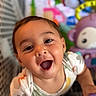 baby, child, toddler, smiling, happy, surprised, portrait, close_up, face, eyes, open_mouth, indoor, playroom, toys, stuffed_animal, colorful, sitting, leaning, short_hair, photography