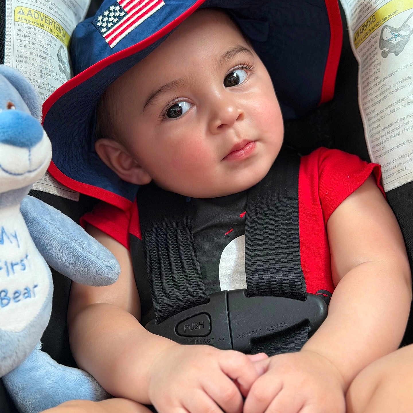 Zayden joined the competition — help win amazing prizes! baby, infant, child, car_seat, seatbelt, hat, american_flag, red_shirt, plush_toy, teddy_bear, smiling, portrait, close_up, indoors, vehicle, passenger, hands,  안전, safety_instructions, photography