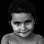Lola participe au concours pour gagner de l'argent avec cette photo : bare_shoulders, black_and_white, child, closeup, cute, dark_background, earrings, emotion, expression, eyes, face, girl, hair, head, innocence, portrait, skin, smile, studio, young
