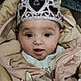 baby, child, tiara, jacket, coat, face, eyes, mouth, clothing, cute, infant, expression, portrait, young_child, indoors, soft_toy, warm, pink, headwear, adorable