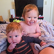 Dallas joined the competition — help win amazing prizes! baby, child, infant, blanket, striped_clothing, smiling, tongue_out, curious, indoor, television, furniture, legs, person, cute, happy, room, cozy, sitting, skin, hair