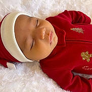 Angelo is registered to the contest to win money with this photo: baby, sleeping, infant, red_clothing, christmas_theme, hat, pajamas, blanket, soft_texture, face, peaceful, cute, holiday, child, portrait, cozy, indoors, resting, young, closed_eyes