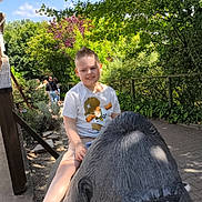 Amenzo a rejoint le concours — aidez-le/la à gagner de superbes lots ! child, boy, statue, gorilla, outdoor, park, greenery, trees, sunny, daylight, casual_clothing, tshirt, shoes, pathway, people, nature, relaxing, playful, sculpture, smiling