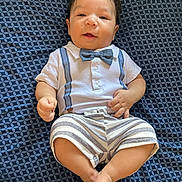 Kaleth is registered to the contest to win money with this photo: baby, child, infant, cute, smiling, bow_tie, striped_shorts, white_shirt, patterned_blanket, lying_down, happy, portrait, young, skin, face, feet, hand, indoors, clothing, person