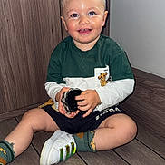Blueboy participe au concours pour gagner de l'argent avec cette photo : toddler, child, smiling, indoor, wooden_floor, green_shirt, white_sneakers, window, toy_brush, shorts, socks, happy, cute, person, flooring, casual_clothing, hair, face, seated, light