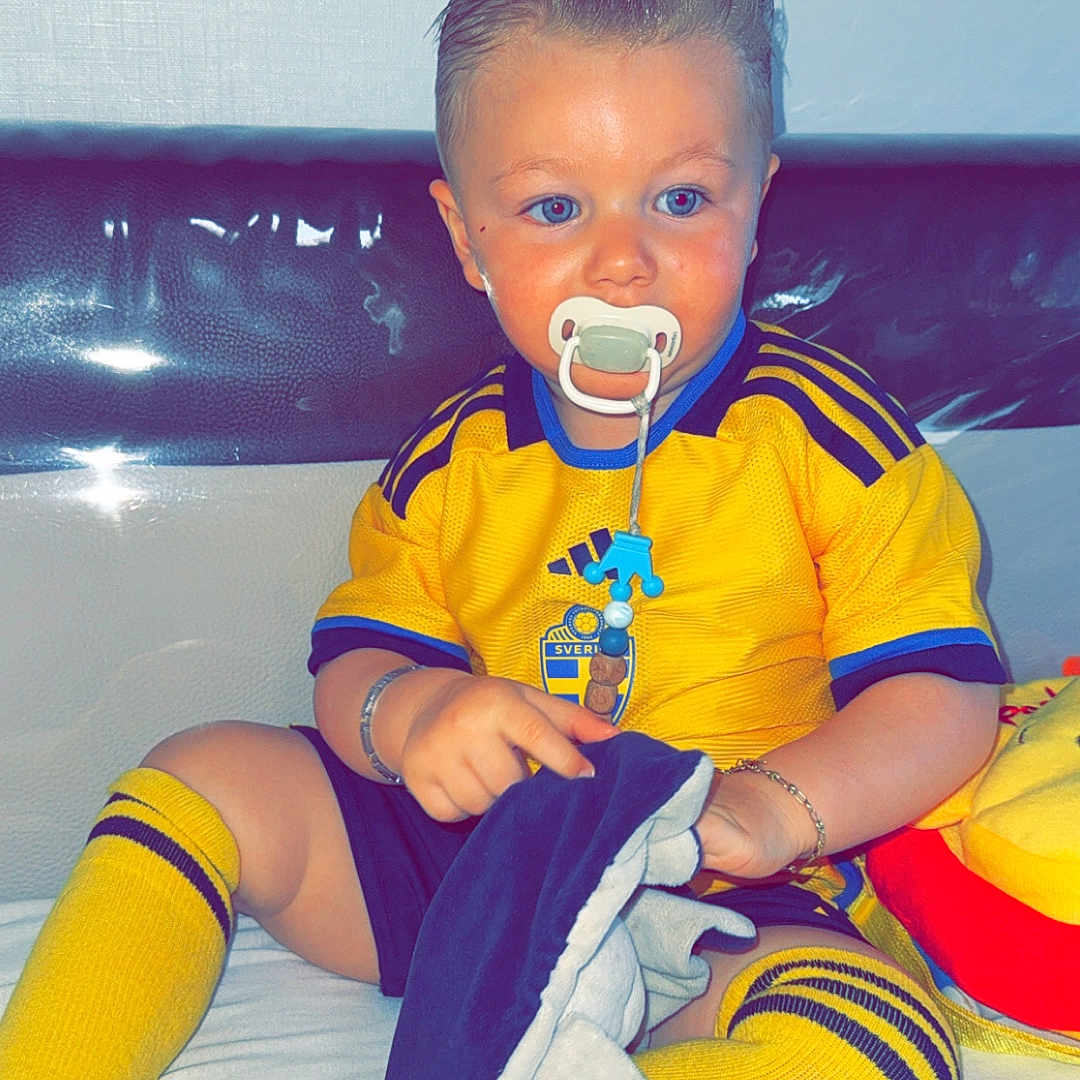 Blueboy a rejoint le concours — aidez-le/la à gagner de superbes lots ! baby, blue_eyes, blue_stripes, bracelet, child, couch, cute, hair_slicked_back, indoors, pacifier, plush_toy, portrait, shorts, sitting, sportswear, toddler, toy, white_background, yellow_shirt, yellow_socks