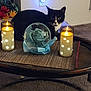 cat, tuxedo_cat, candle, glass_orb, rose, flower, table, mat, indoor, decor, light, glow, plant, flowerpot, carpet, furniture, cozy, black_and_white, still_life, relaxing