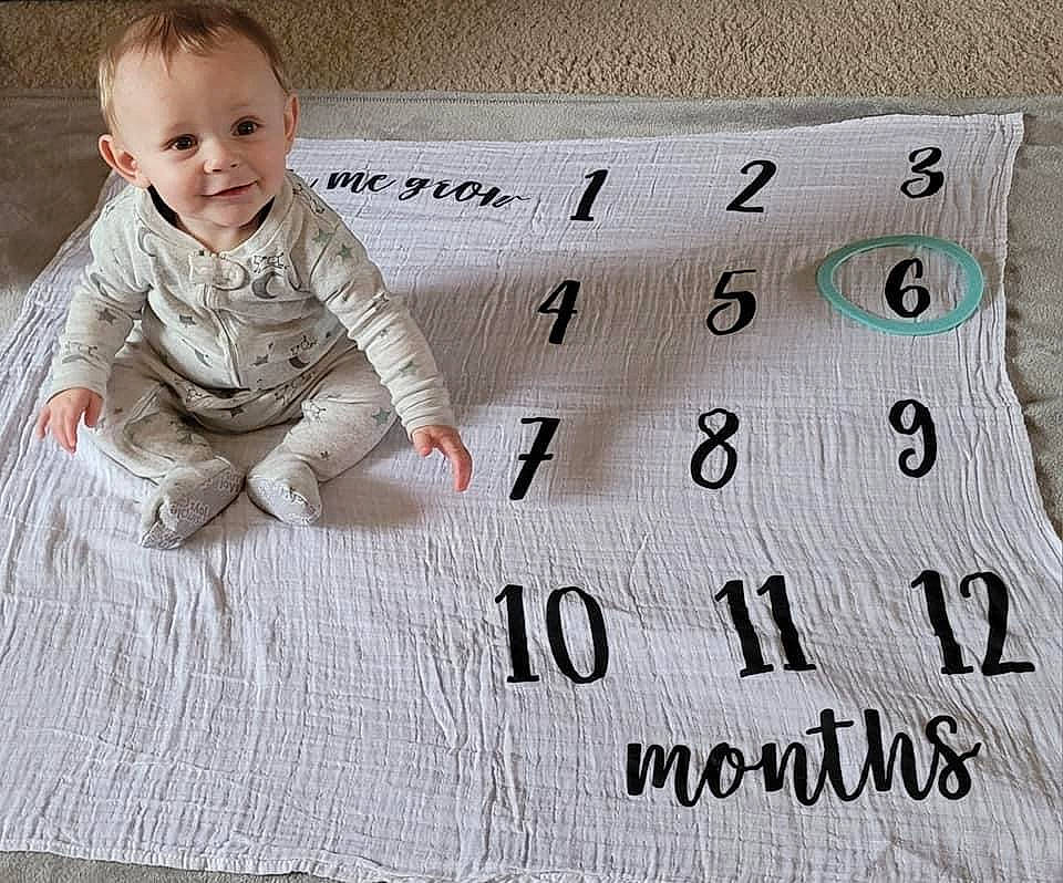 Brantley is registered to the contest to win money with this photo: baby, baby_toddler_clothing, child, comfort, crawling, flooring, font, happy, hardwood, joy, linens, number, pattern, person, photo_caption, rectangle, sitting, sleeve, smile, textile