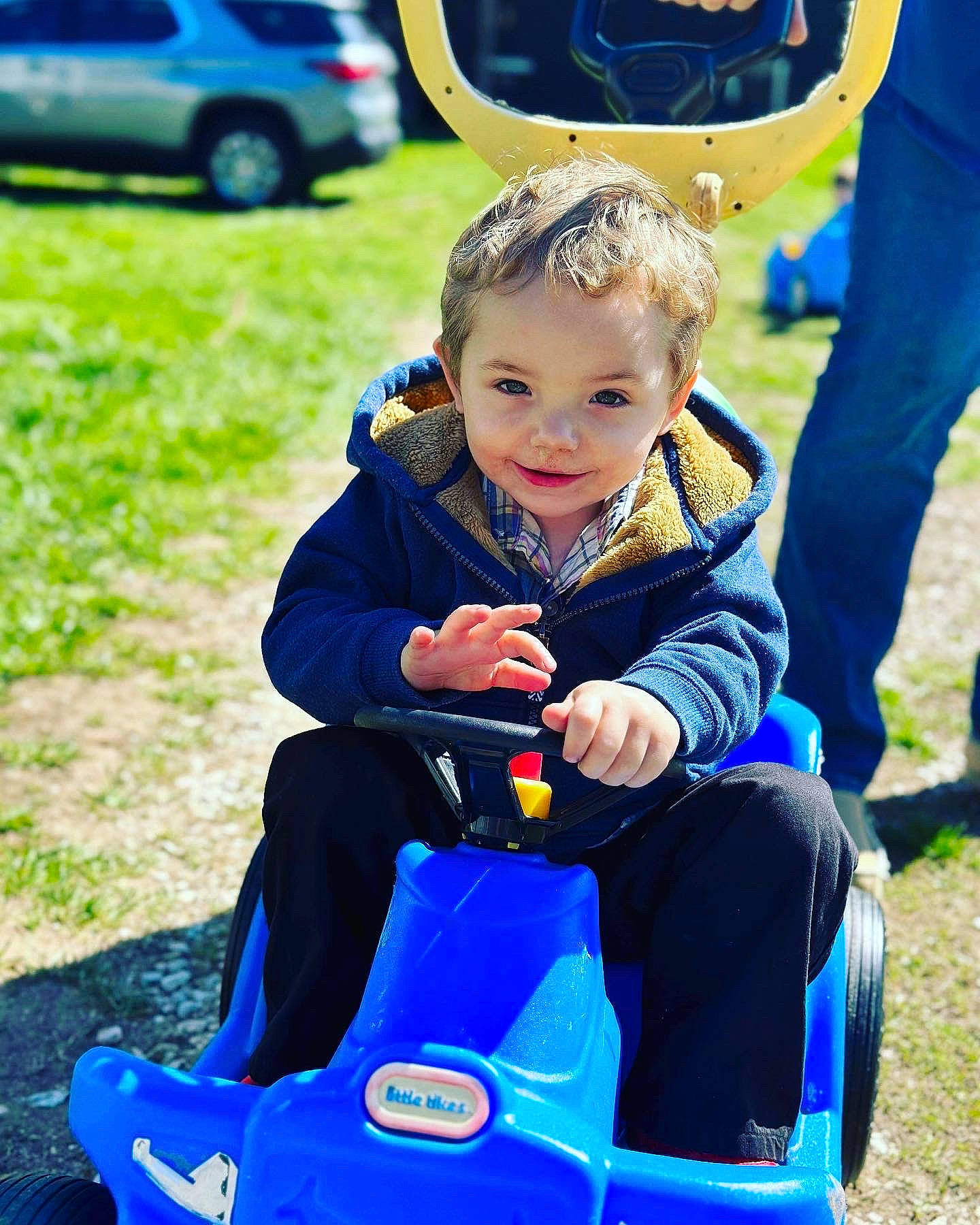 Tanner Flannery is registered to the contest to win money with this photo: baby, blue, car, electric_blue, event, fun, grass, green, happy, joy, lawn, leisure, motor_vehicle, person, recreation, riding_toy, sitting, smile, sneakers, tire